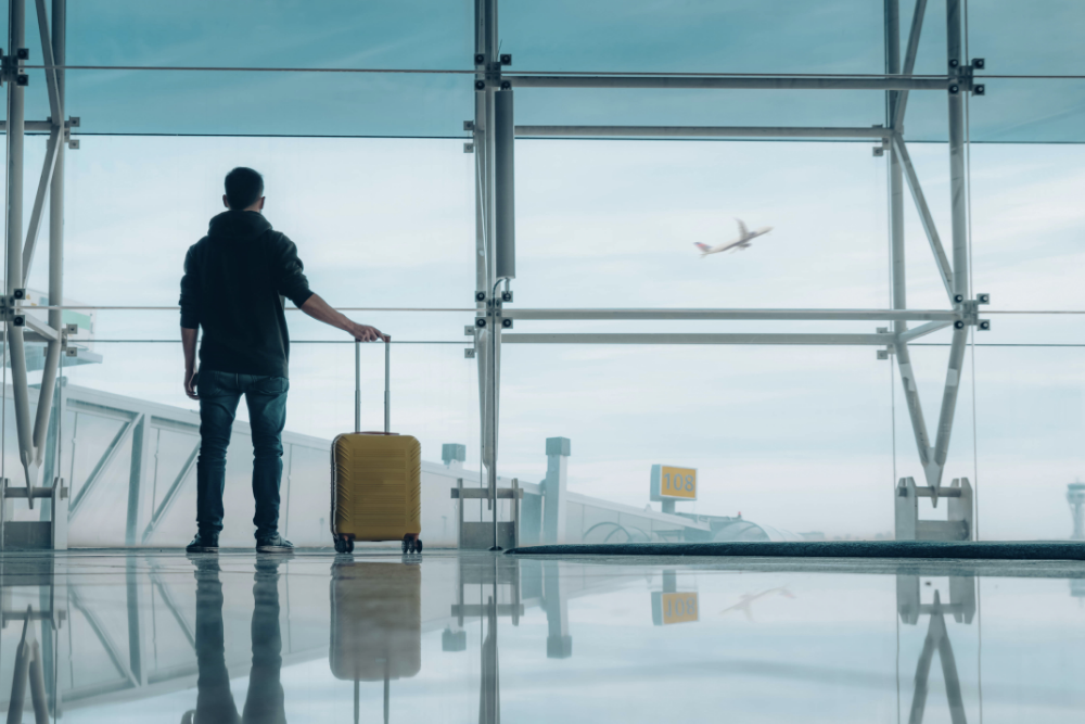 Person stood alone in empty airport with suitcase